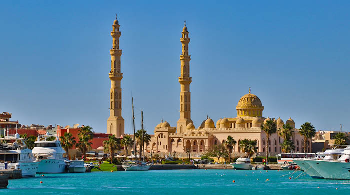 Huge mosque in Hurghada, Egypt called El Mina Masjid photographed from harbour with lots of yachts and boats near coast of Red sea.